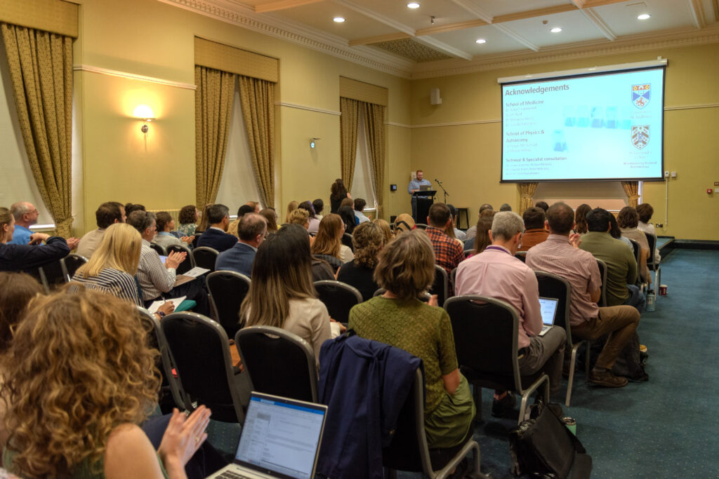 An full audience listens to a presentation.